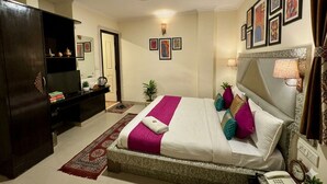 A hotel room with a large bed, a television, a desk, and a wardrobe. - Shoba Residency  (New Delhi)