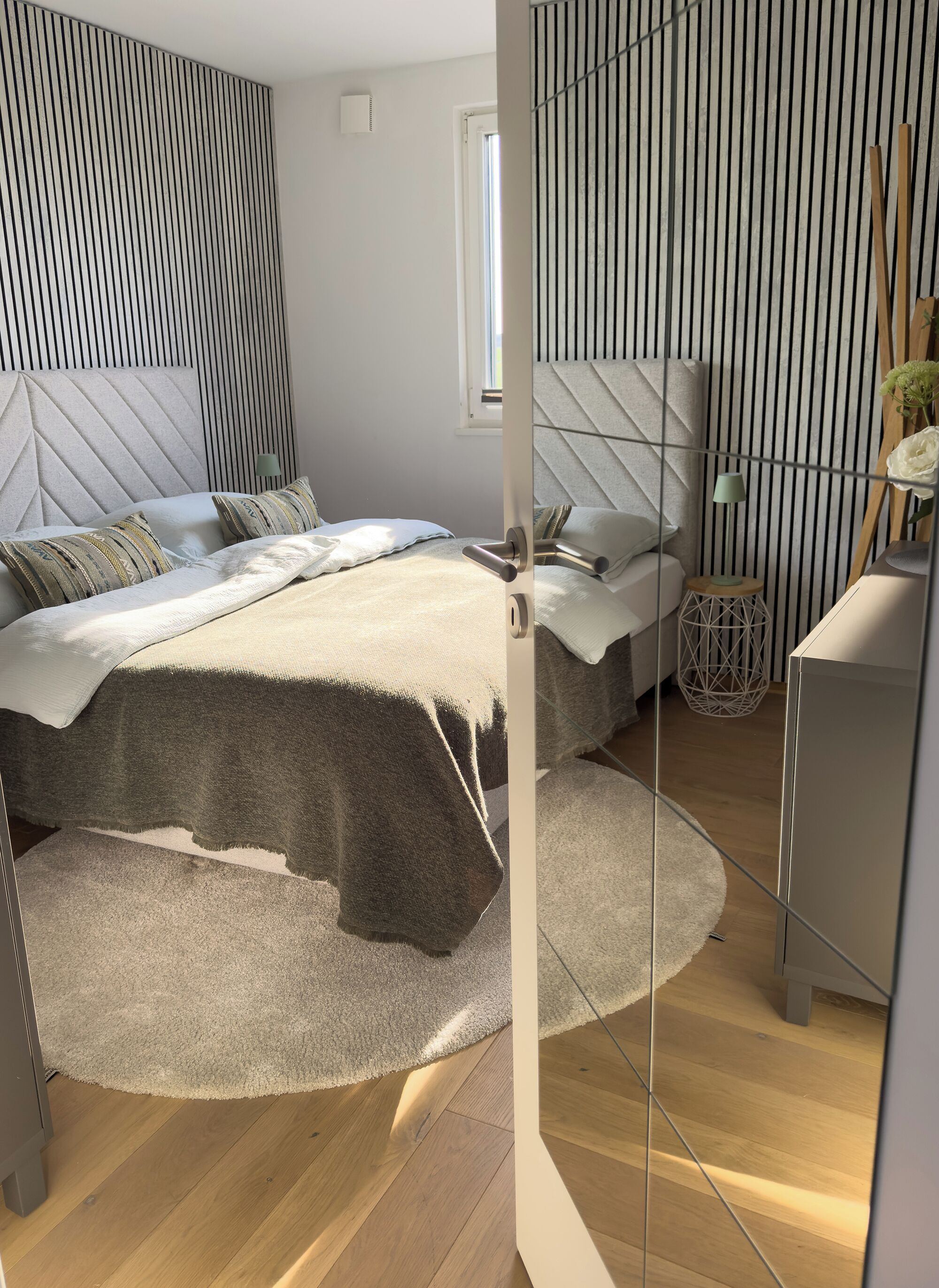 Un dormitorio moderno con cama, mesitas de noche y un espejo.