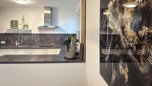 Uma cozinha moderna com bancada de mármore, eletrodomésticos de aço inoxidável e vista para uma sala de jantar.