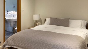 Une chambre d’hôtel avec un lit, une table de chevet avec une lampe et vue sur la salle de bain.