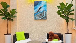 Un espace patio aménagé avec deux fauteuils en osier, une petite table ronde et deux plantes en pot.