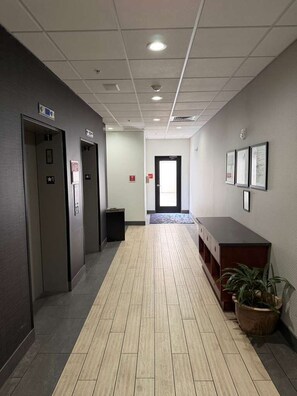 A hallway with elevators, a reception desk, and a potted plant. - Surface Boutique Hotel, Will Rogers Airport, Fairgrounds, Restaurant & Bar (Oklahoma City)