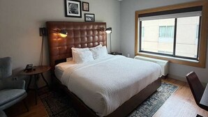 A bedroom with a large bed, a chair, a small table, a standing lamp, and a window. - Surface Boutique Hotel, Will Rogers Airport, Fairgrounds, Restaurant & Bar (Oklahoma City)