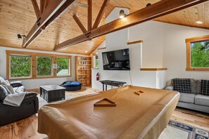 A spacious living area with a large wooden ceiling, a sofa, a coffee table, and a television mounted on the wall. - Family Getaway Carnelian Bay! Pool Table, Stone Fireplace, & Large Backyard (Carnelian Bay)
