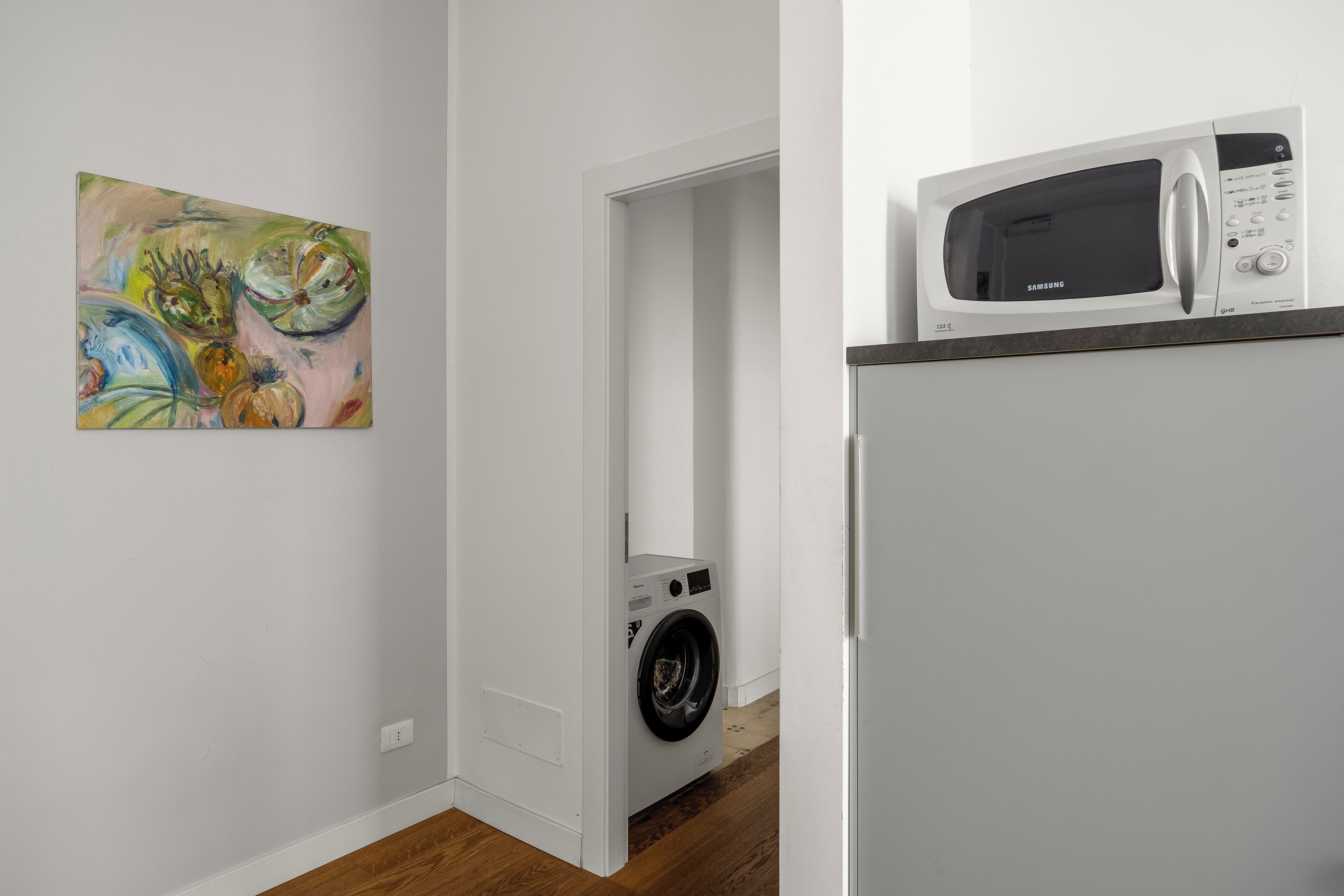 A laundry room with a washing machine and a microwave on a counter.