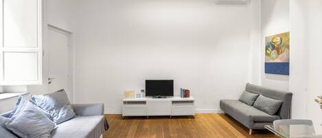 A modern living room with a grey sofa, a white entertainment unit, and a grey couch.