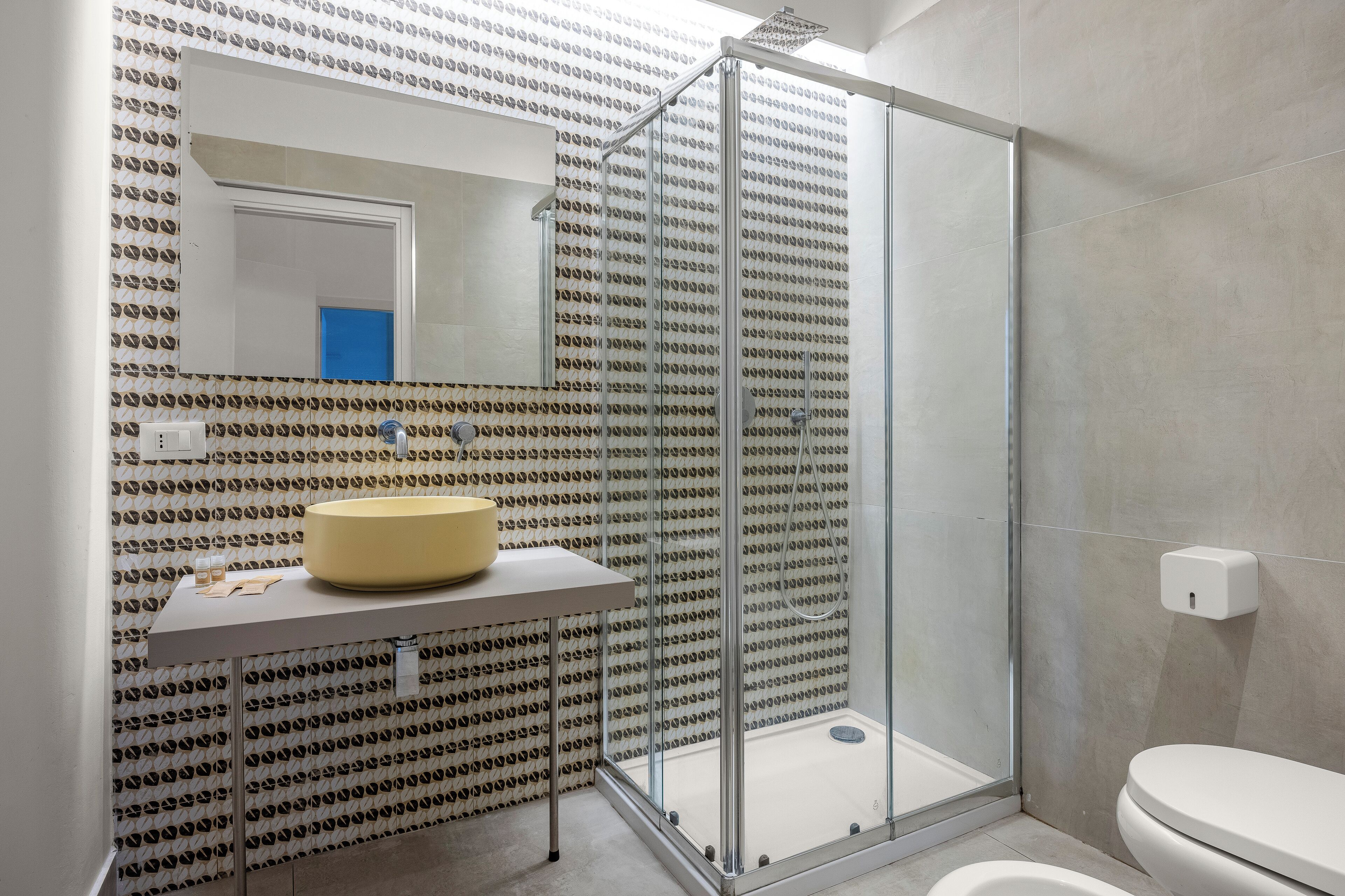 Ein modernes Badezimmer mit Duschkabine aus Glas, einem beigen Waschbecken und einer weißen Toilette.