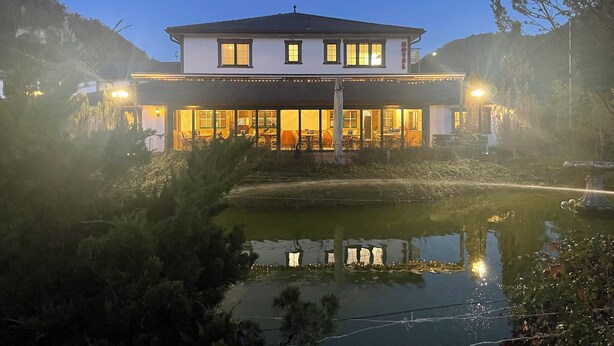 A two-story hotel with a large front porch and a pond in front. - Hôtel Restaurant Le Cavalier (Soyhières)