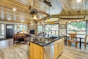 A spacious kitchen with a large island, wooden cabinetry, and a stone fireplace. - < 1 Mi to Chico Hot Springs: Mtn-view Hideaway! (Pray)