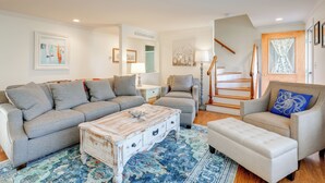 A living room with a sofa set, a coffee table, a patterned rug, and a staircase leading to another level. - 6 Mi to Beach: Home w/ Deck in Brewster! (Brewster)