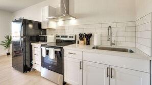 A modern kitchen with stainless steel appliances, white cabinetry, and a tiled backsplash. - Phoenix Casita 11 Mi to Dtwn, Baseball & More (Phoenix)