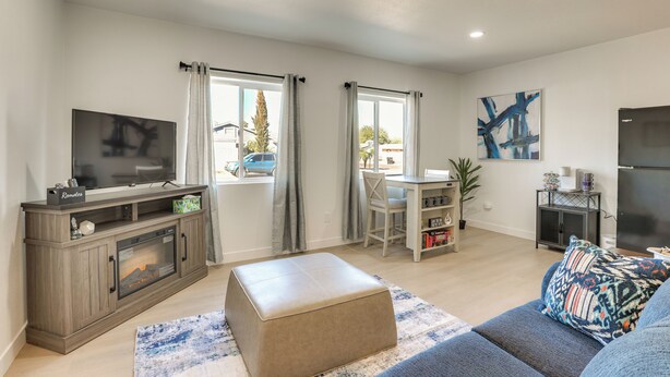 A living room with a TV, entertainment unit, ottoman, sofa, and a dining area with a table and chairs. - Phoenix Casita 11 Mi to Dtwn, Baseball & More (Phoenix)