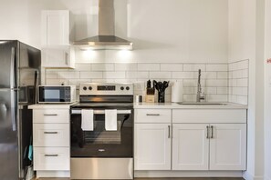 Une cuisine moderne dotée d’appareils électroménagers en acier inoxydable, de meubles blancs et d’un dosseret carrelé.