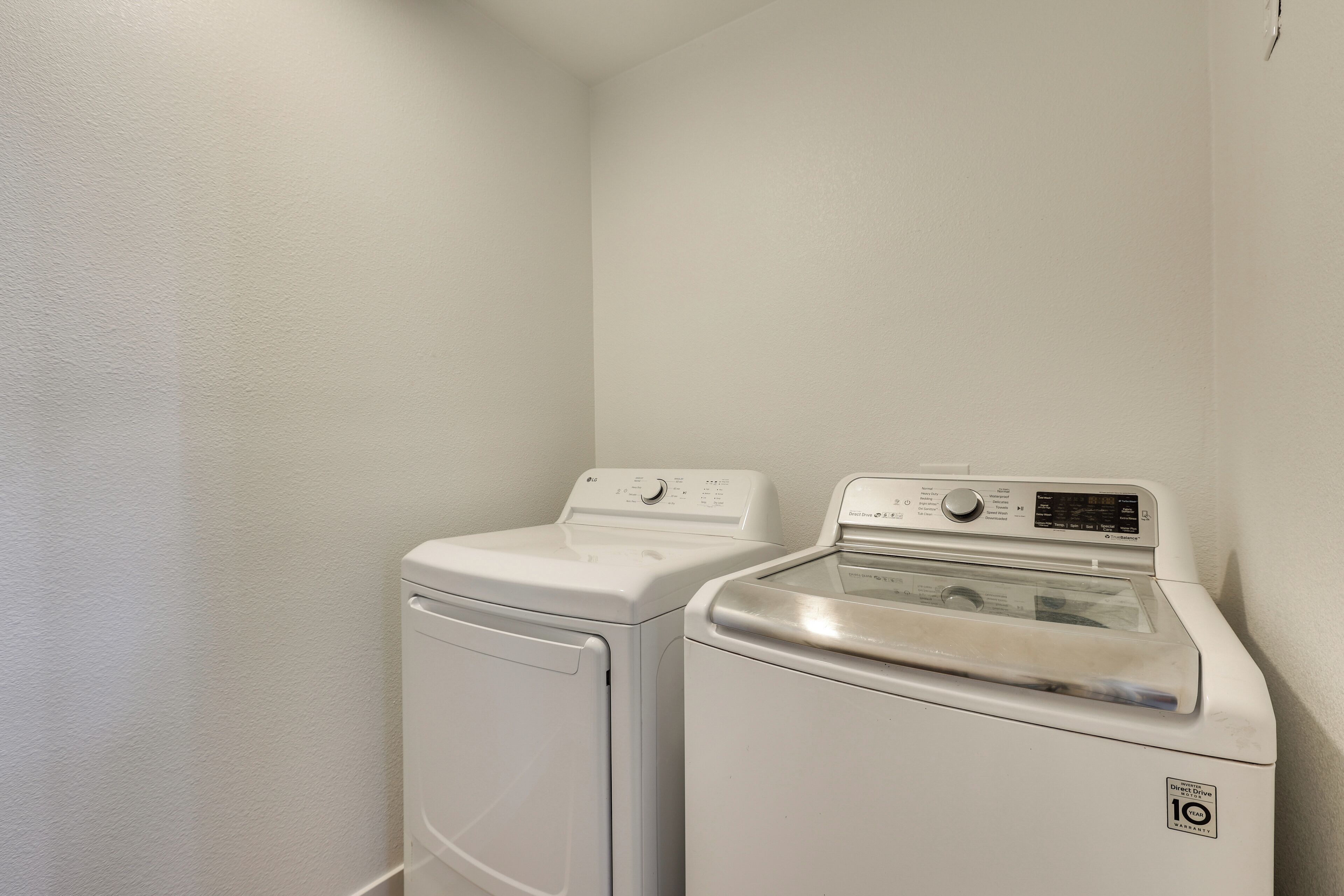 A laundry room with two white washing machines and a dryer.