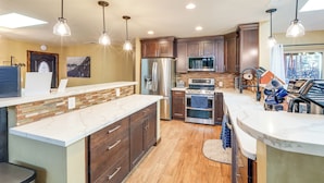 A modern kitchen with wooden cabinets, stainless steel appliances, and pendant lighting. - Gazebo w/ View & EV Charger: Rustic Williams Cabin (Williams)