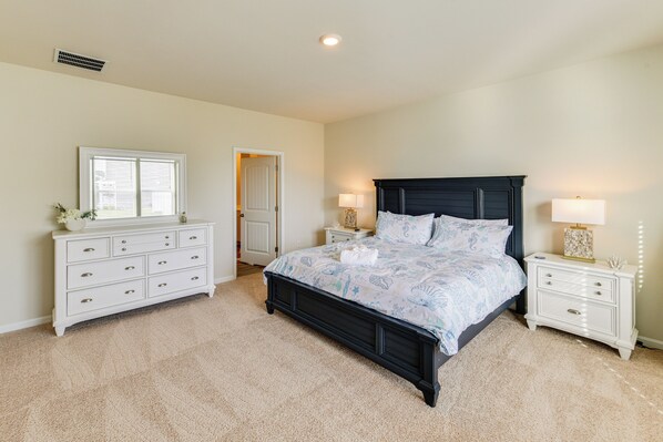 A bedroom with a large bed, a dresser, a nightstand, and a window. - 5 Mi to Bethany Beach: Home w/ Pool + Gym Access! (Millville)