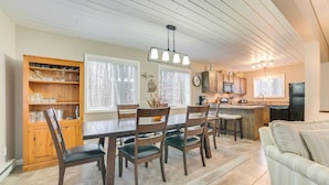A kitchen with wooden cabinets, a dining table with chairs, a refrigerator, and a coffee maker.