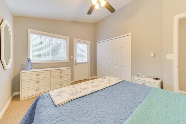 A bedroom with a bed, dresser, closet, and windows.