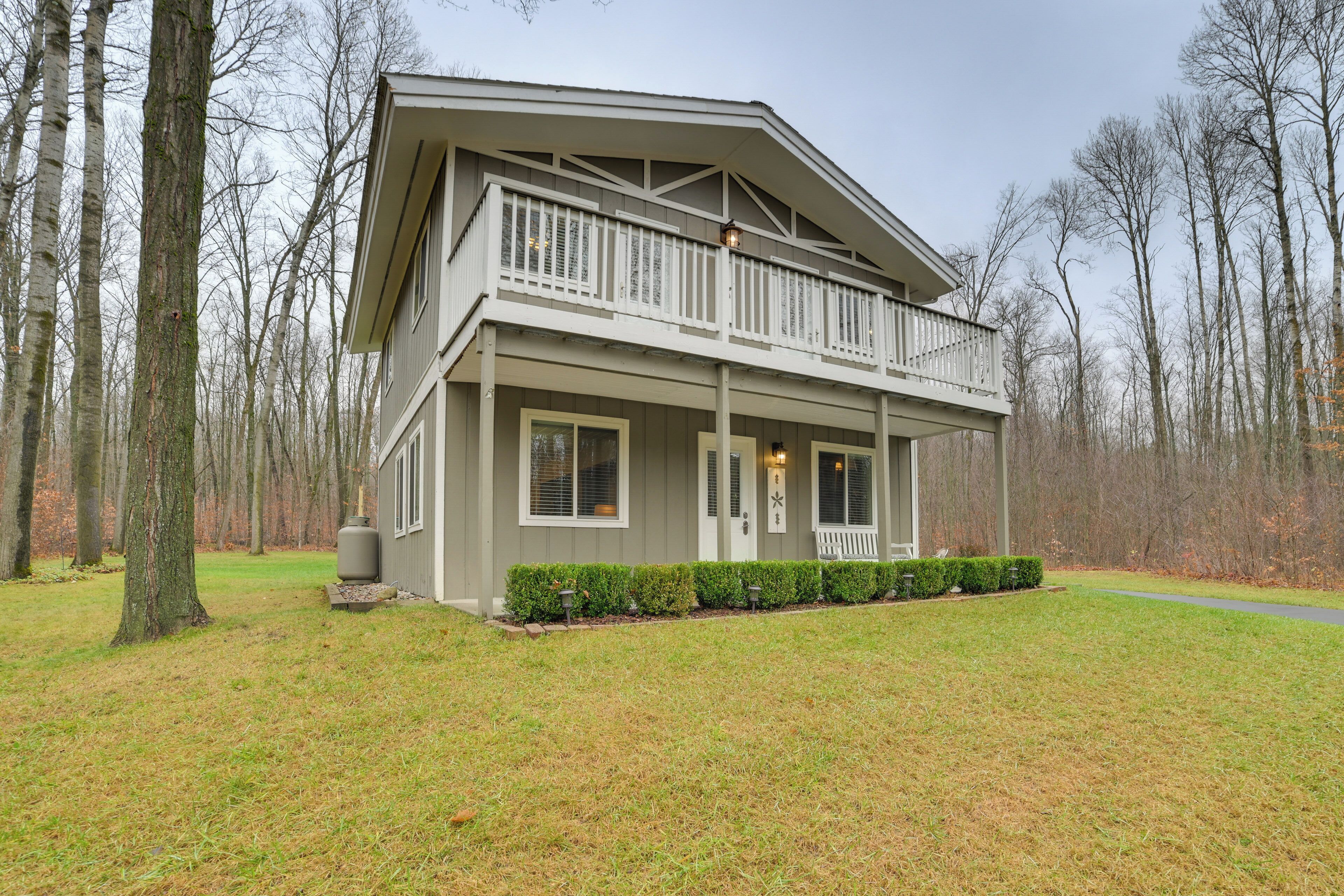 A two-story house with a balcony, surrounded by trees and a well-maintained lawn.