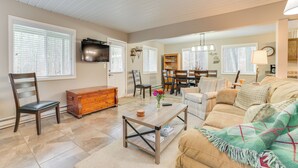 A spacious living room with a wooden coffee table, a beige sofa, and a dining area with a chandelier.