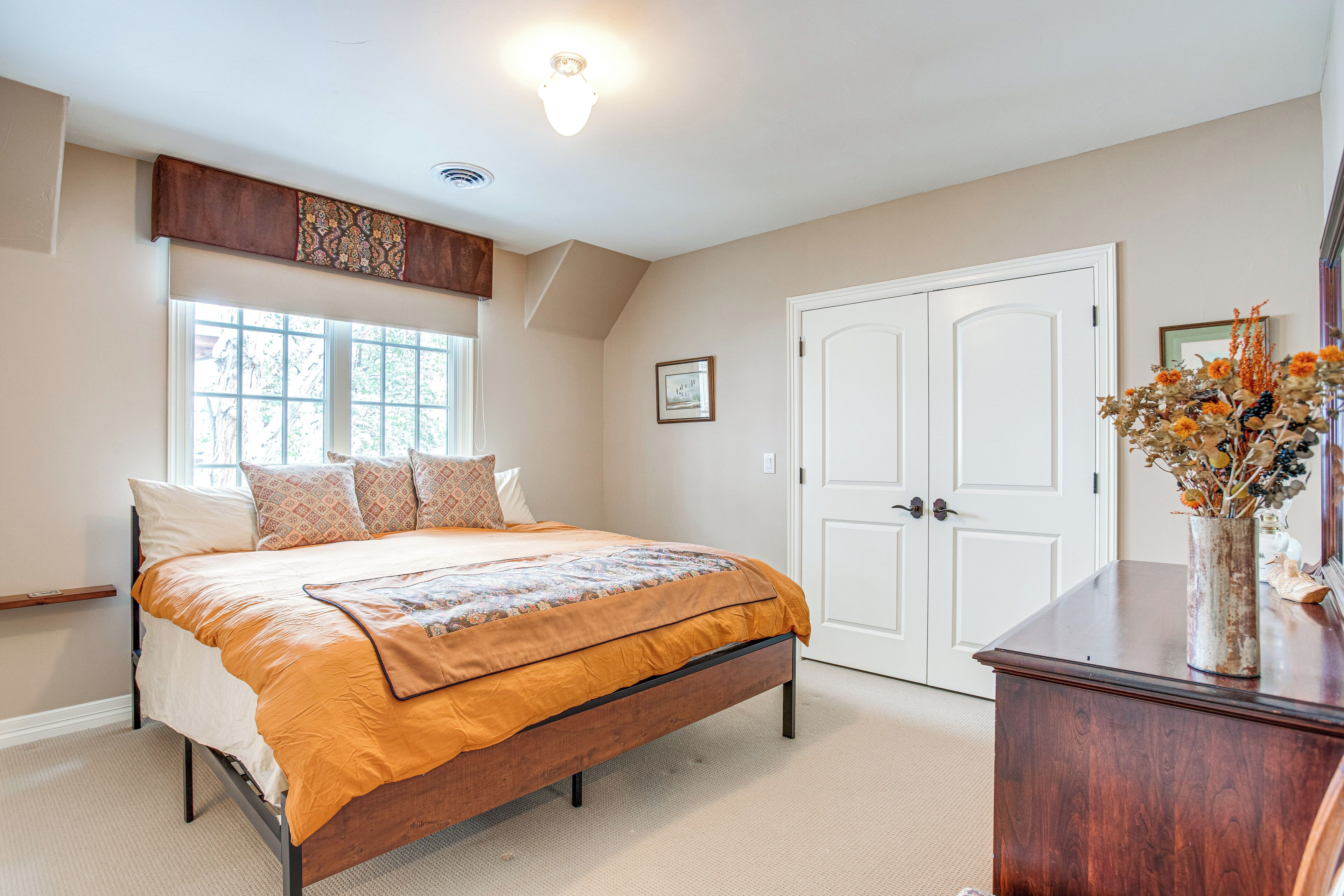 A bedroom with a bed, a dresser, a window, and a door.