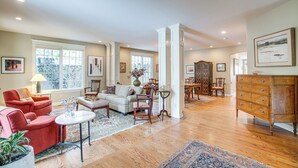 A spacious living room with a fireplace, a dining area, and a large wooden cabinet. - Walk to DU, Dining & Parks: Spacious Denver Home! (Denver)