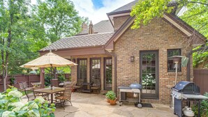 A brick house with a patio, outdoor seating, and a grill. - Walk to DU, Dining & Parks: Spacious Denver Home! (Denver)