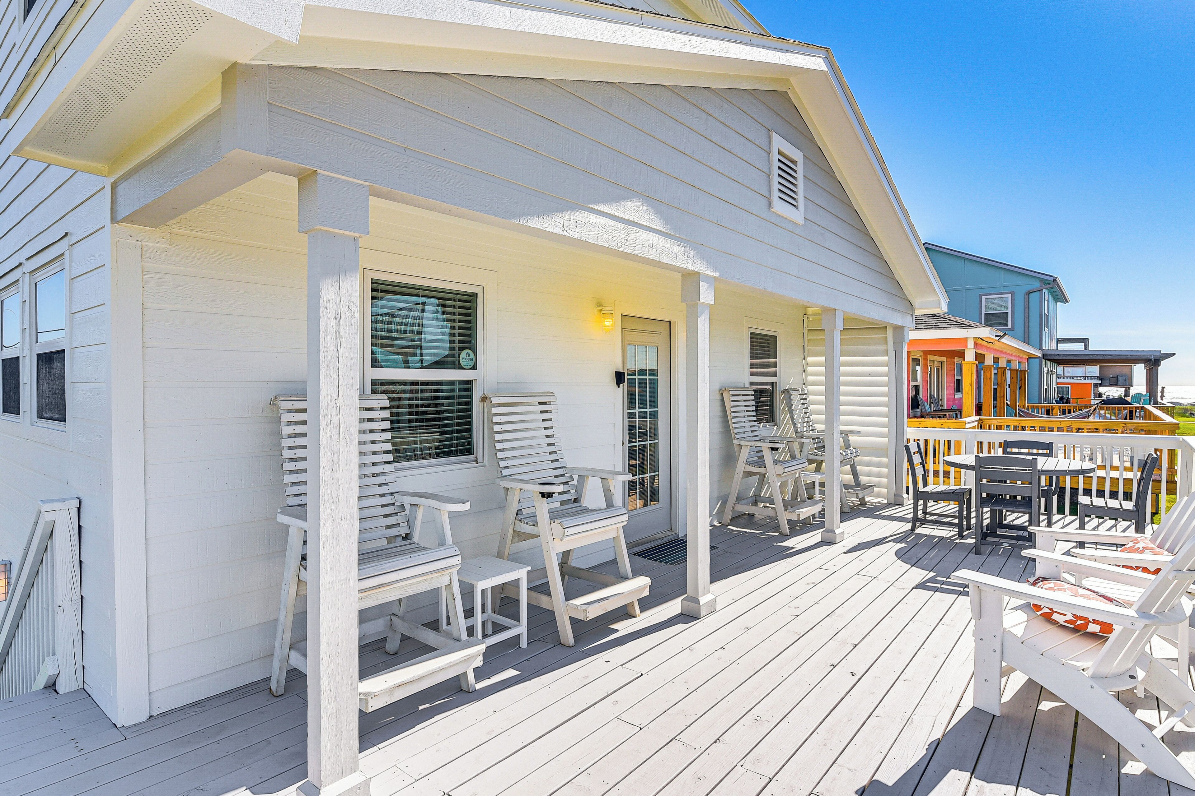 A white wooden house with a porch, outdoor seating, and a small table.