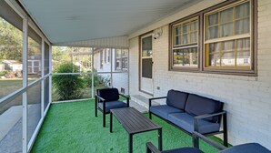 A covered patio with a green artificial turf, a sofa, two chairs, and a small table. - Near Fort Liberty: Home w/ Yard in Fayetteville! (Fayetteville)