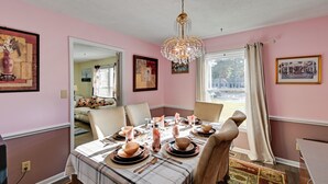 A dining room with pink walls, a chandelier, and a table set for six. - Near Fort Liberty: Home w/ Yard in Fayetteville! (Fayetteville)