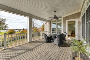 A covered porch with a table and chairs, a ceiling fan, and a view of the surrounding landscape.