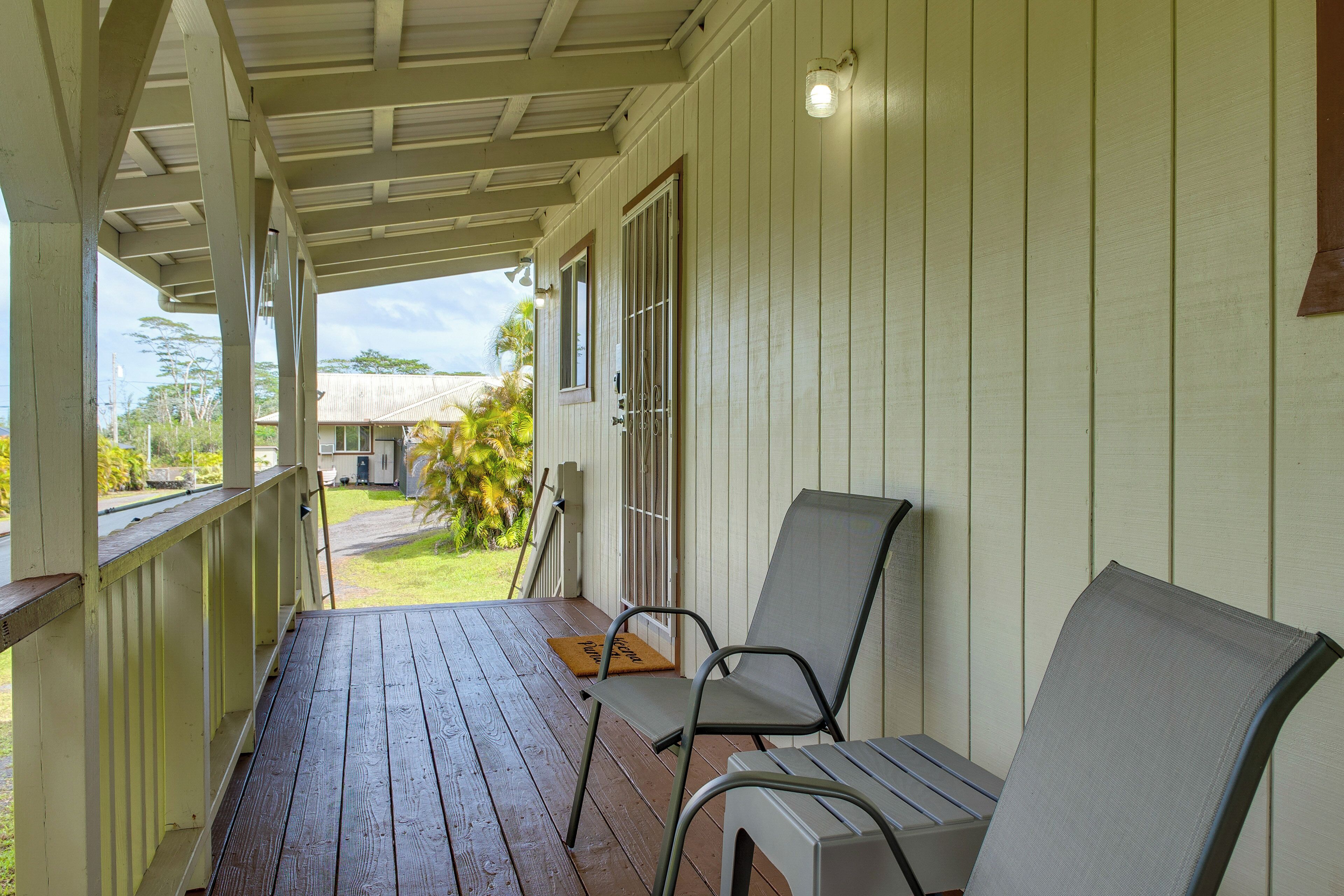 A covered porch with two chairs and a wooden door.