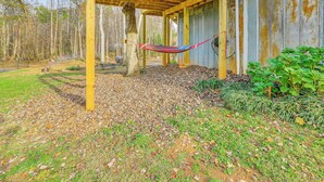 A wooden deck with a hammock, surrounded by trees and a gravel path. - Countryside Gem on Homestead in Asheboro! (Asheboro)