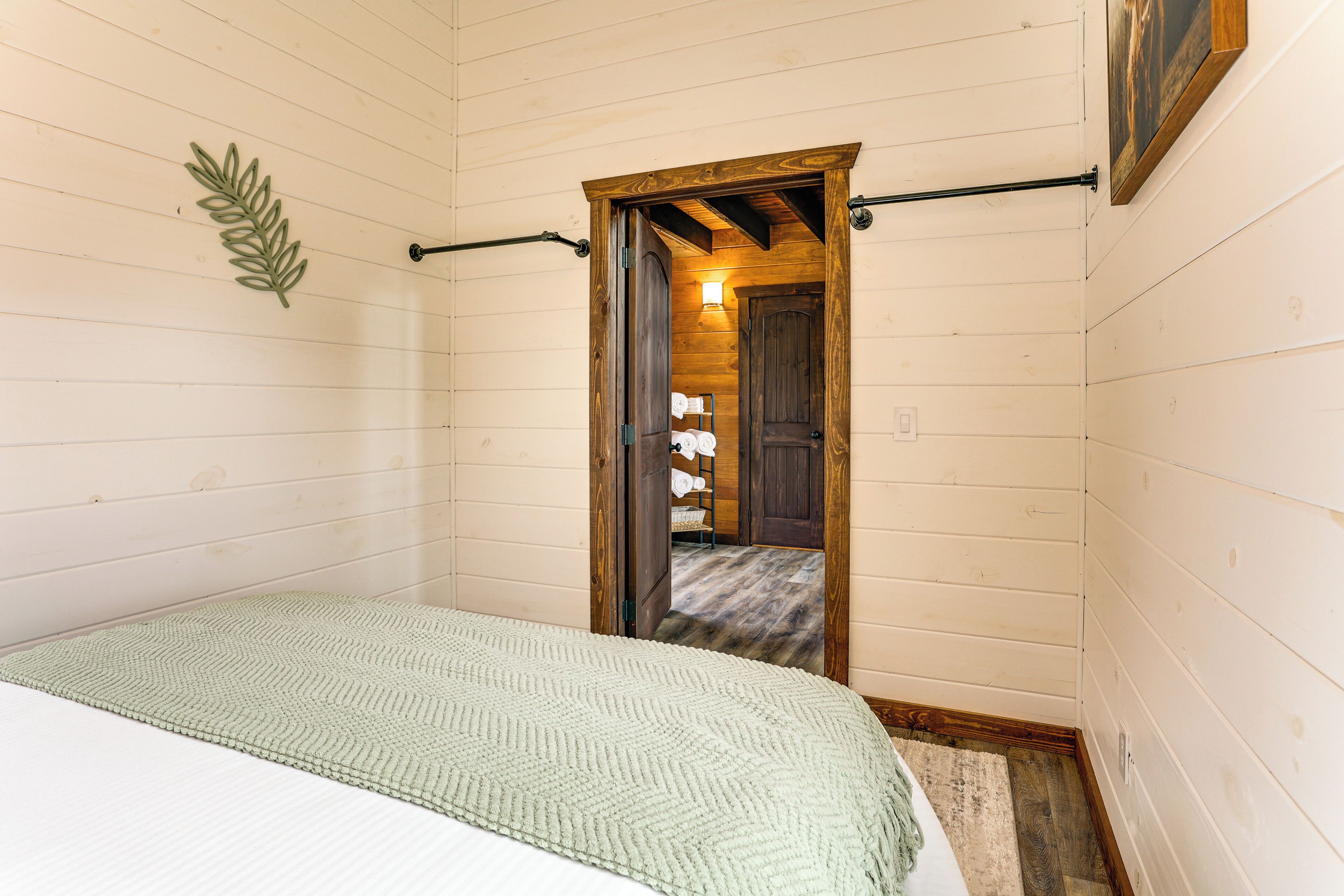 Een slaapkamer met een bed, een houten deur en een gang die naar een badkamer leidt.