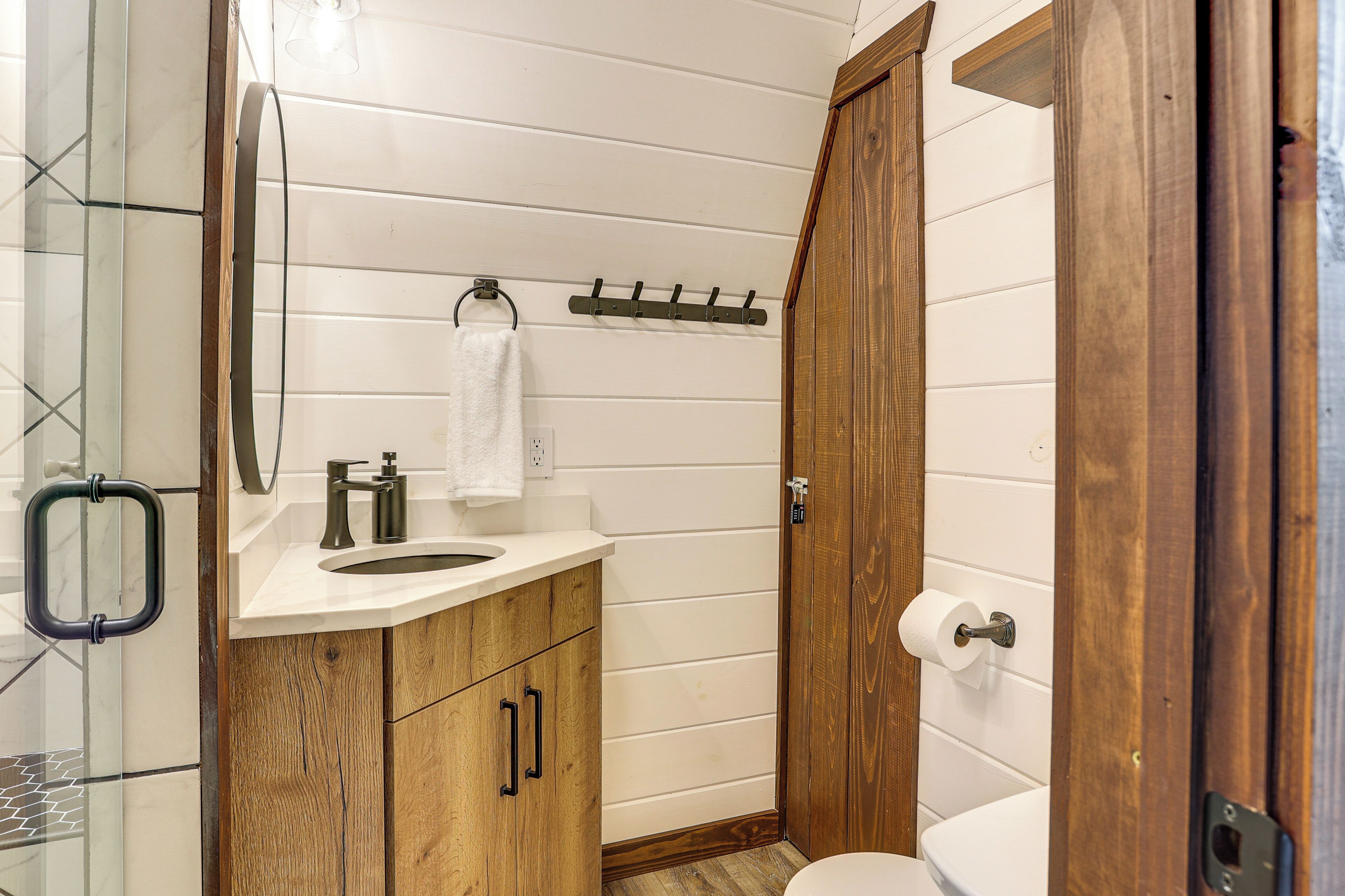 A bathroom with wooden cabinets, a white sink, a mirror, and a toilet.