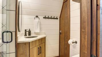 A bathroom with wooden cabinets, a white sink, a mirror, and a toilet.