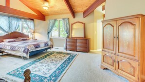 Un dormitorio con techo de madera, una cama, un aparador y un espejo grande.