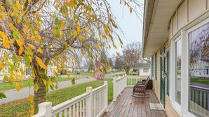 A wooden porch with a white railing, a bench, and a welcome mat. - Walk to Sandusky Bay: Home w/ Hot Tub & Fire Pit! (Sandusky)