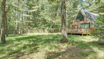 A cabin with a wooden deck, surrounded by a forest.
