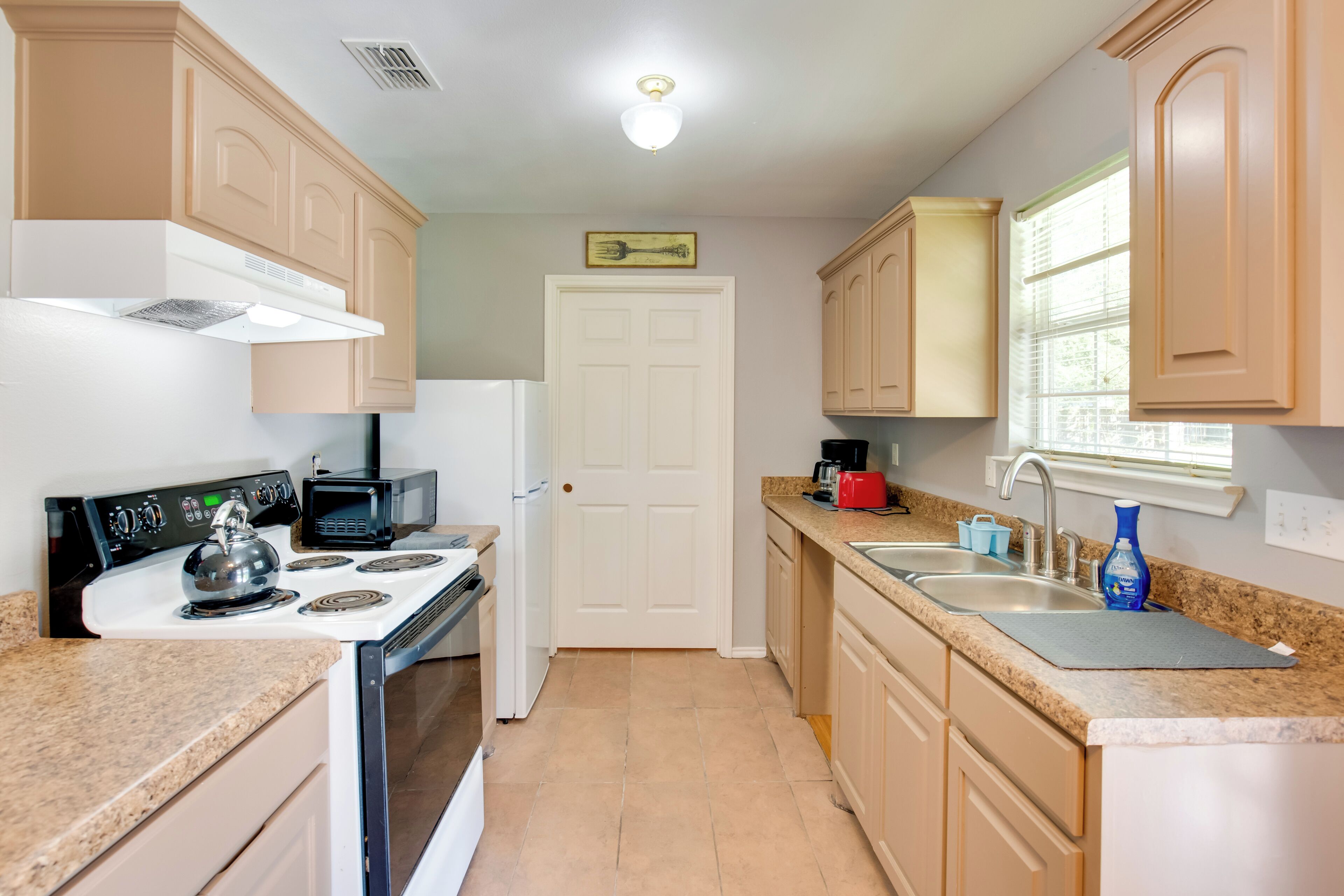 A kitchen with a stove, microwave, sink, and cabinets.