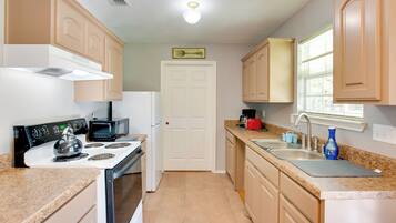 A kitchen with a stove, microwave, sink, and cabinets.