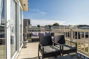 Un balcón con mobiliario de mimbre y vistas a una zona residencial.