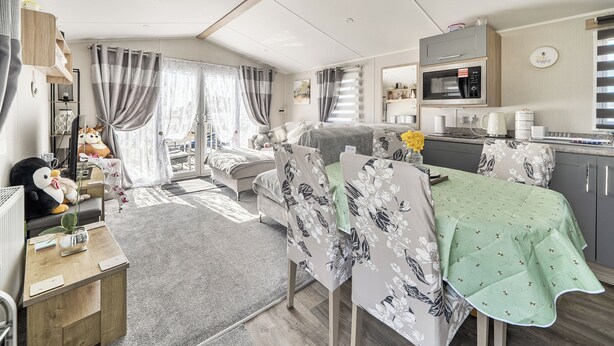 Ett kompakt bostadsutrymme med ett litet kök, en säng, en matplats och en liten sittgrupp.