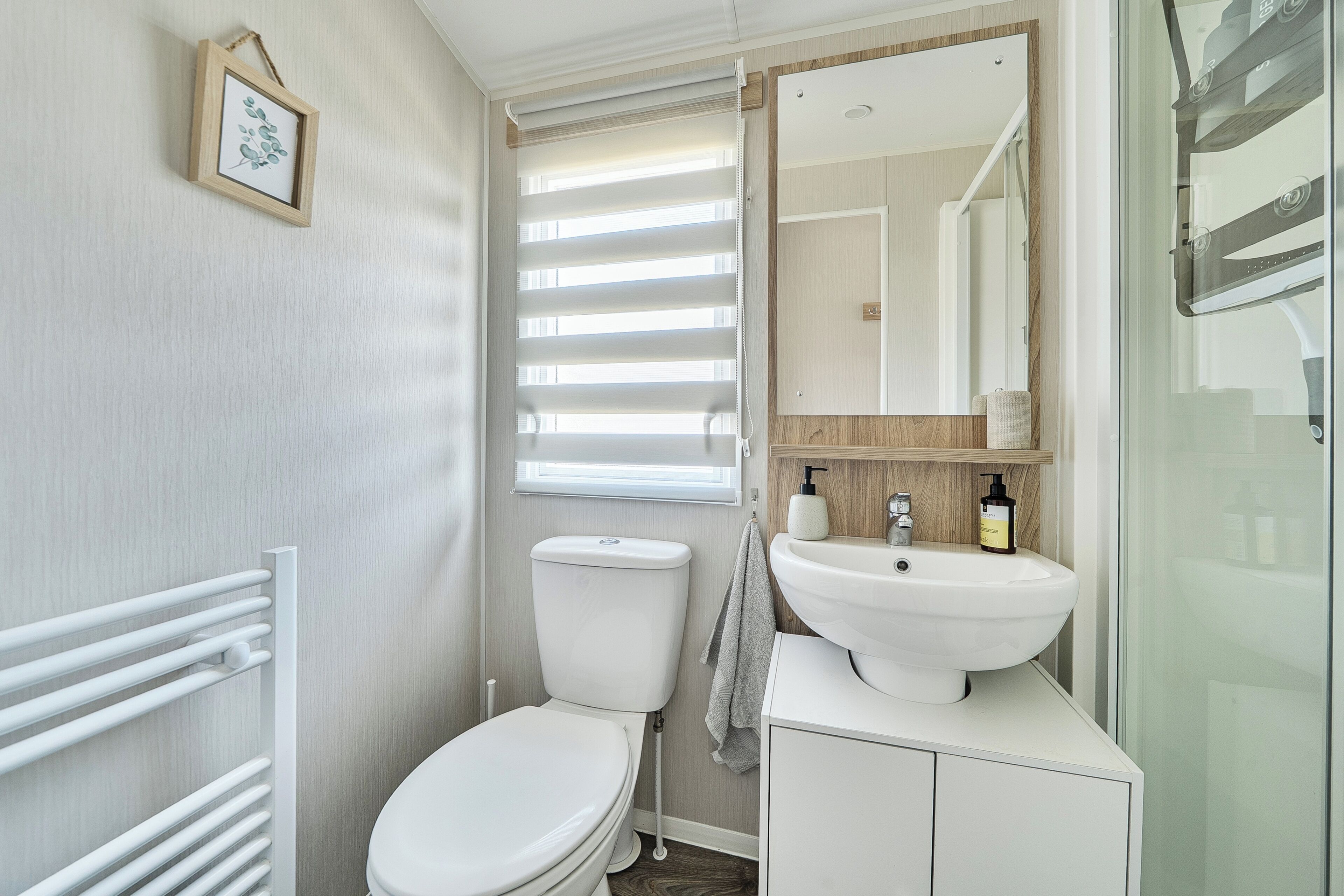 A bathroom with a toilet, a sink, a mirror, and a towel rack.
