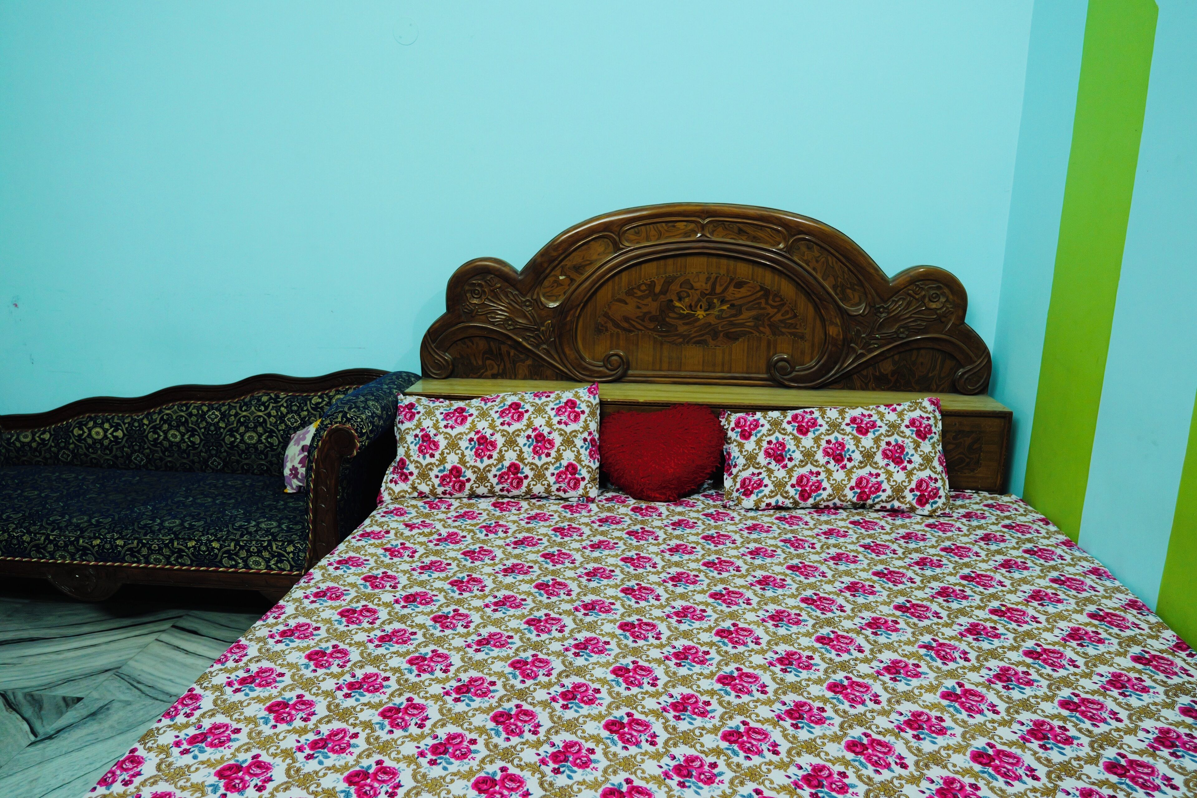 A bed with a floral bedspread and a wooden headboard.