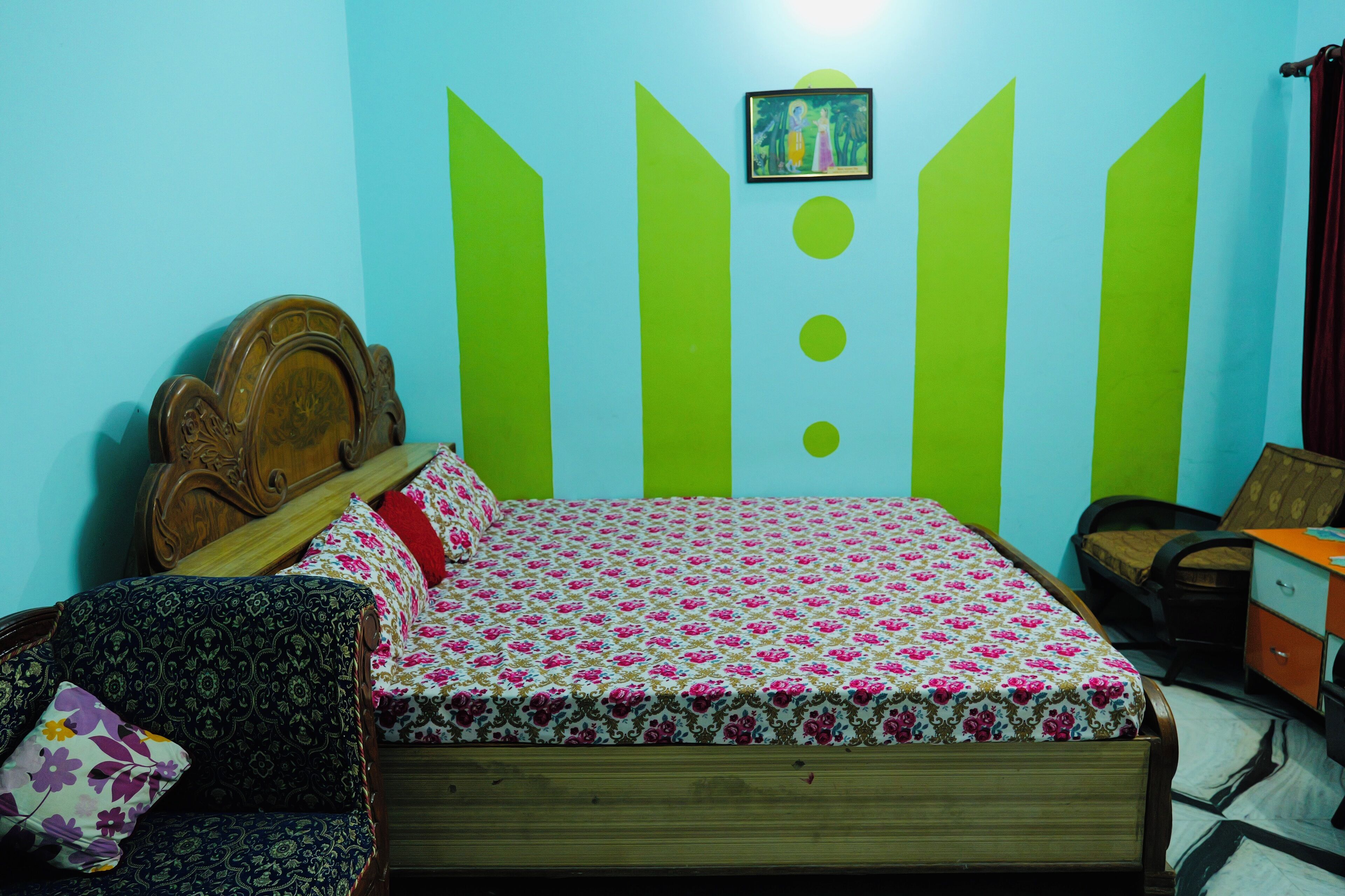 A bedroom with a wooden bed, a patterned sofa, and a wall with geometric designs.