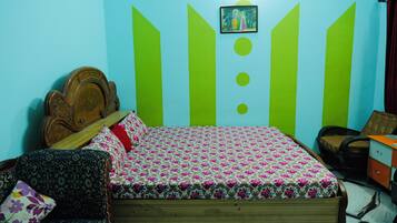 A bedroom with a wooden bed, a patterned sofa, and a wall with geometric designs.