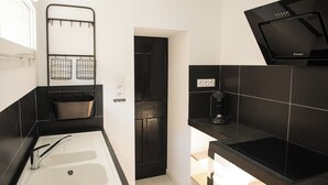 Una cocina moderna con encimeras negras, un lavamanos blanco, una puerta negra y una estufa negra.