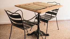 A table with two chairs, a woven placemat, and a speckled floor.