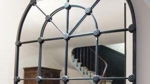 A mirror with a black metal frame and a geometric design.
